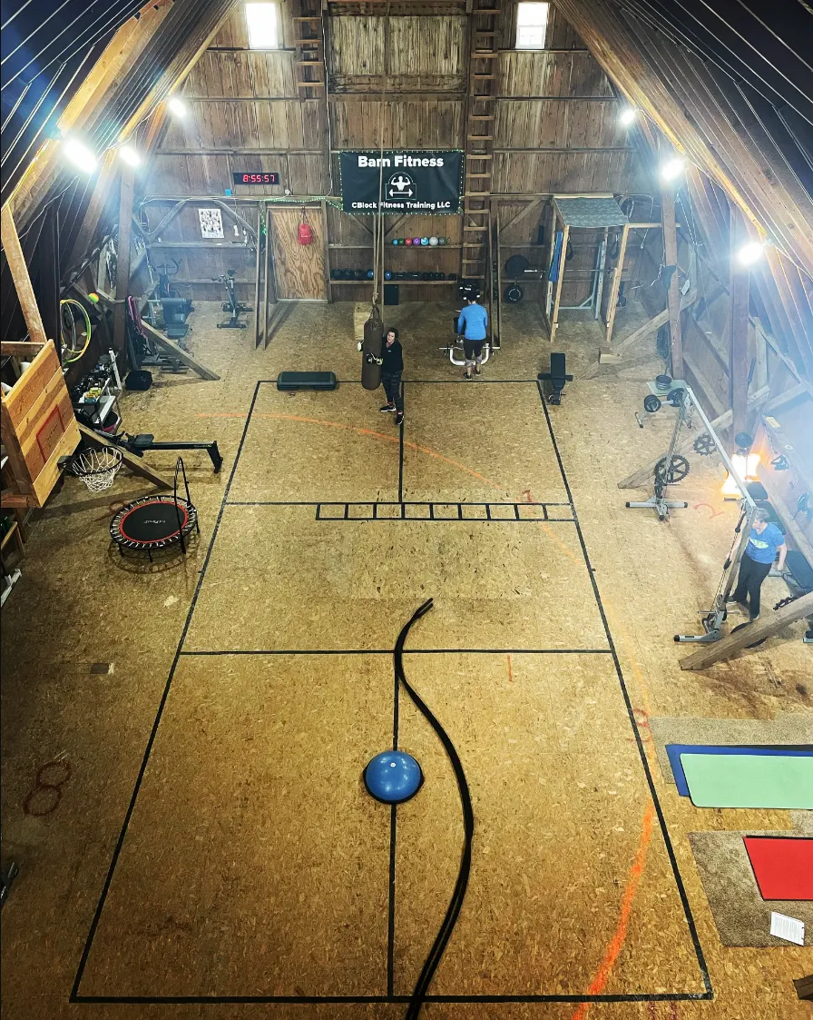 View from the hayloft of the Barn Fitness workout floor with cardio machines, racks and strength equipment
